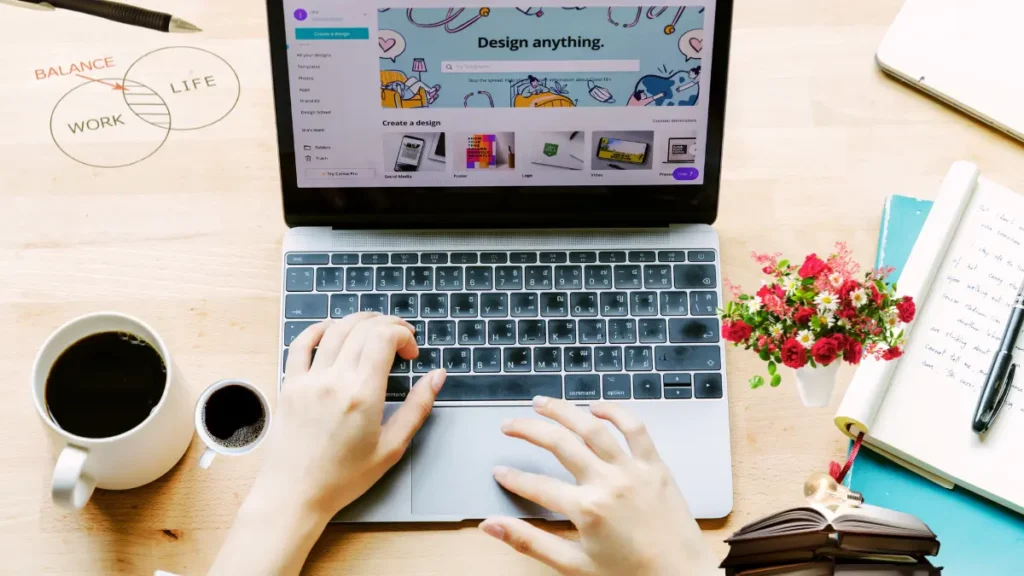 Freelancer working on Canva with coffee and notebook.