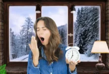 Tired woman yawning in the morning holding alarm clock, feeling unrested after sleep