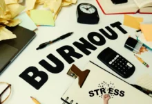 Desk cluttered with papers, calculator, clock, and the word burnout—symbolizing stress and why you can’t focus