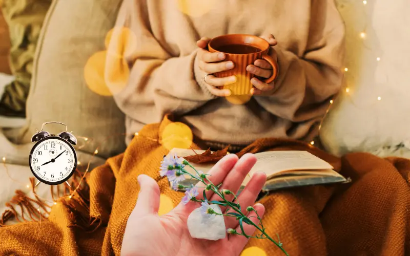Person holding tea and relaxing with a book in a cozy setting.