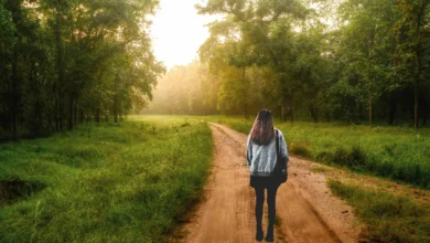 Person walking quietly through forest at sunrise, practicing silent walking for mental clarity