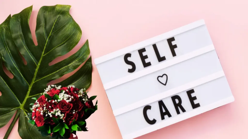 Self-care signboard with red flowers and tropical leaf promoting emotional wellbeing.
